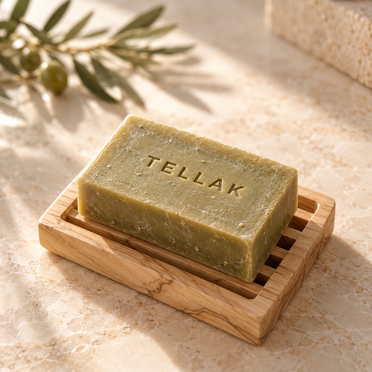 Tellak olive oil soap bar stamped with the Tellak name on a wooden soap dish